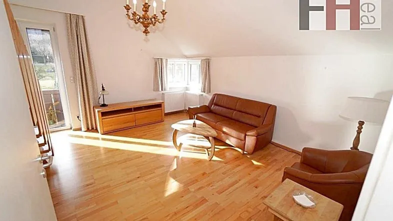 Helles Wohnzimmer mit Parkettboden, braunen Ledermöbeln und Zugang zum Balkon.