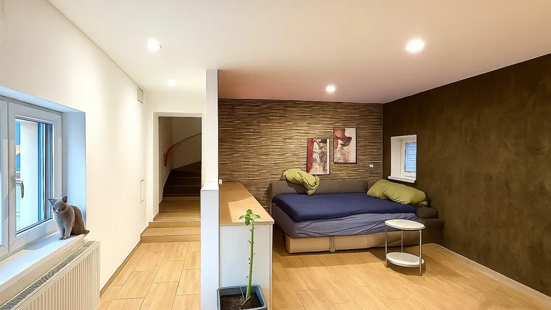 Heller Wohnbereich mit Fliesenboden, Fenster und einer Katze auf der Fensterbank.