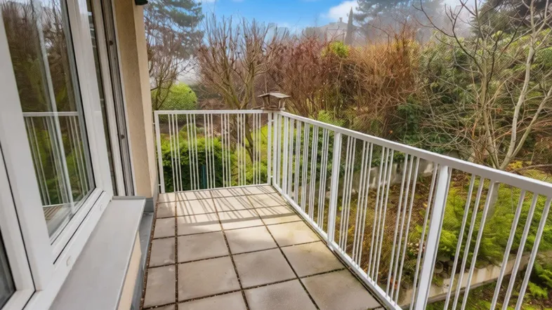 Heller Balkon mit Fliesenboden und Blick ins Grüne, ideal für entspannte Stunden im Freien.