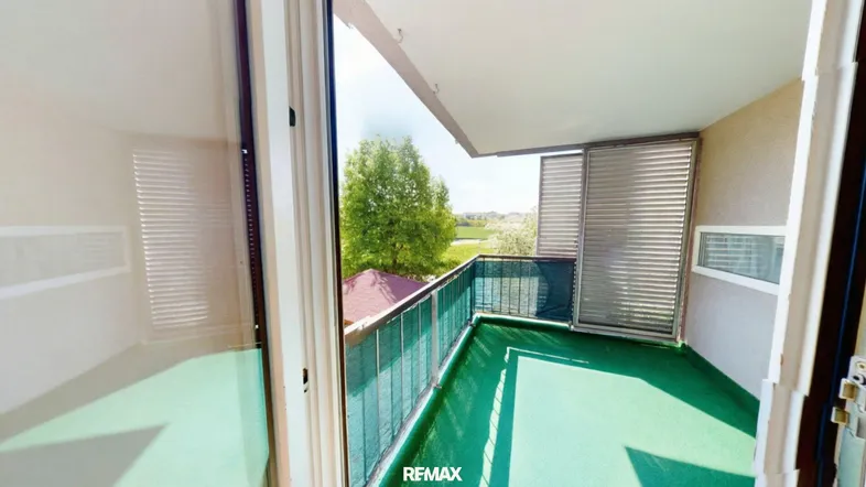 Heller Balkon mit Kunstrasen und Blick ins Grüne, ideal zum Entspannen im Freien.