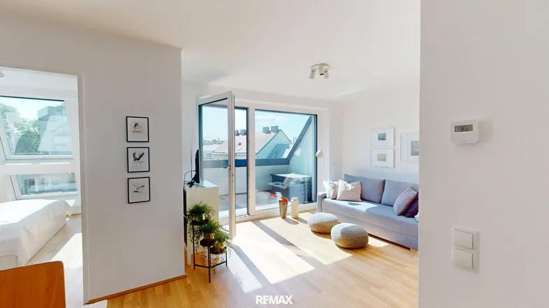 Helles Wohnzimmer mit Holzboden, Zugang zum Balkon und Blick auf die Stadt.