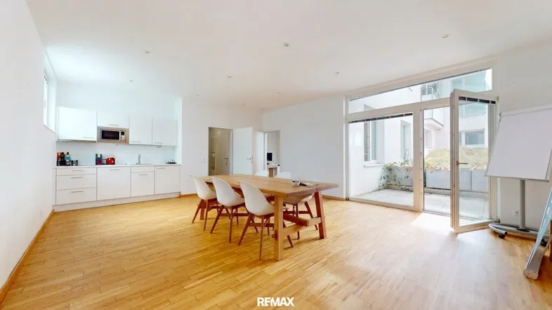 Großer, heller Büroraum mit integrierter Küchenzeile, Esstisch und Zugang zur Terrasse.