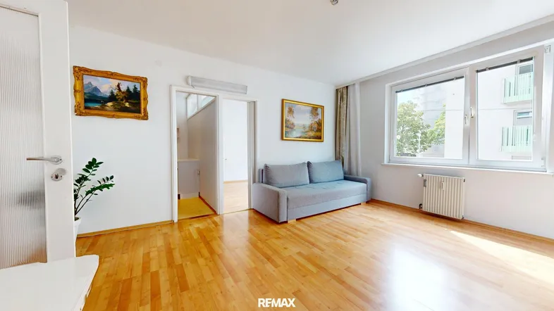 Helles Wohnzimmer mit Parkettboden, einem Sofa und Blick auf die gegenüberliegenden Balkone.