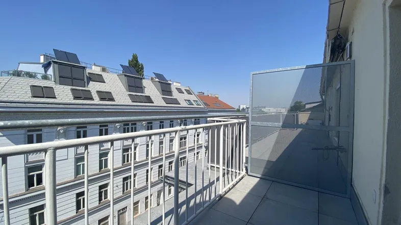 Geräumiger Balkon mit Fliesenboden und Blick auf umliegende Gebäude und Dächer mit Solaranlagen.