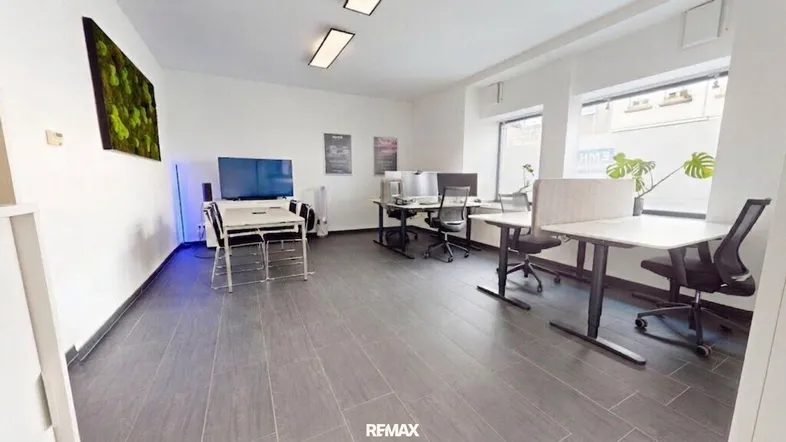 Geräumiges und helles Büro mit mehreren Arbeitsplätzen, modernen Möbeln und großen Fenstern.