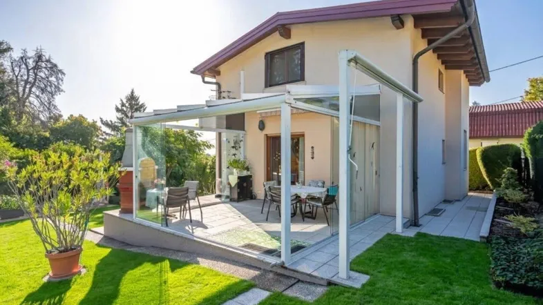 Überdachte Terrasse mit Gartenmöbeln und Blick auf den grünen Gartenbereich des Hauses.