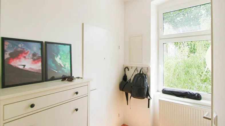 Heller Eingangsbereich mit Schuhschrank, Garderobe und Fenster mit Blick ins Grüne.