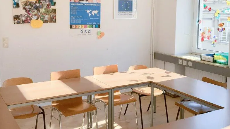 Heller Raum mit Tischen und Stühlen, ideal für Besprechungen oder Unterricht, mit viel Tageslicht.