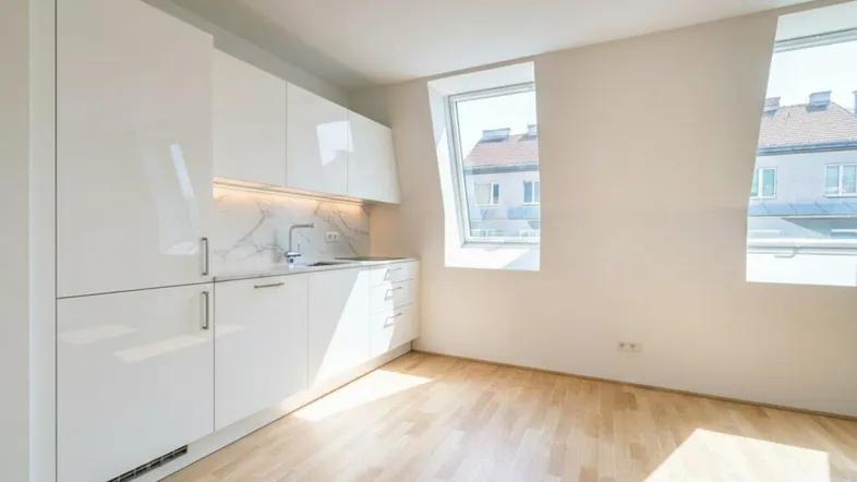 Moderne, helle Küche mit weißen Hochglanzfronten, Marmor-Rückwand und Dachfenstern.
