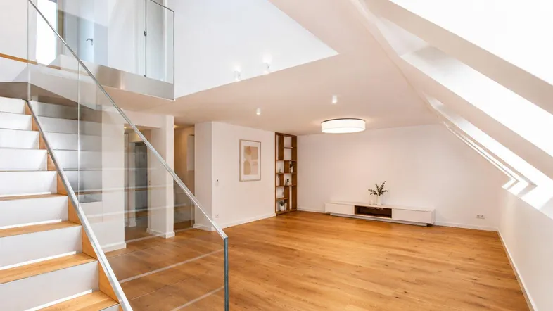 Helles Wohnzimmer mit Holzboden, moderner Treppe und Dachschrägenfenstern.