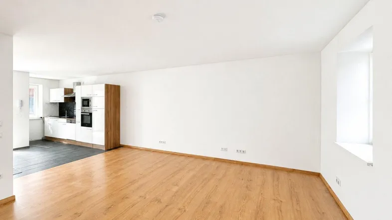 Heller offener Wohnbereich mit Laminatboden und integrierter Küche, ideal für modernes Wohnen.