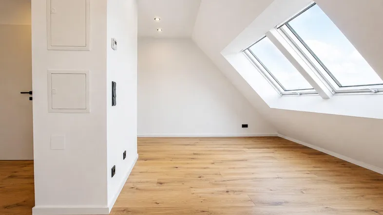 Helles Dachgeschosszimmer mit Holzboden und großen Dachfenstern, ideal für individuelle Gestaltung.
