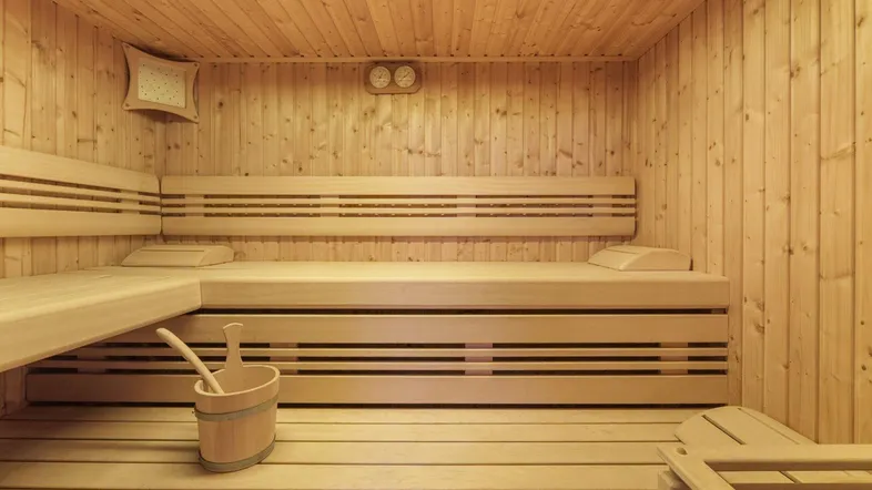 Helle Holzsauna mit Bänken und traditionellem Zubehör für entspannende Momente.