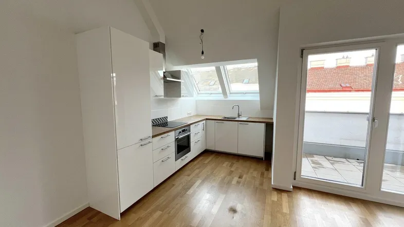 Moderne Küche mit weißen Schränken, Holzarbeitsplatte, Dachfenstern und Zugang zur Terrasse.