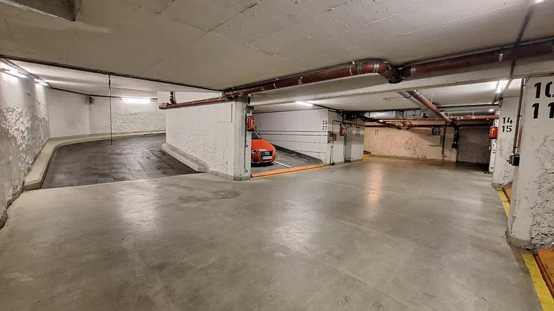 Tiefgarage mit mehreren Stellplätzen und hydraulischen Parksystemen für Fahrzeuge.