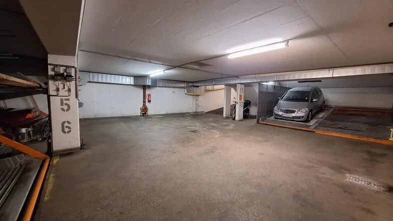Tiefgarage mit hydraulischen Parksystemen und mehreren Stellplätzen für Fahrzeuge in einem Mehrfamilienhaus.