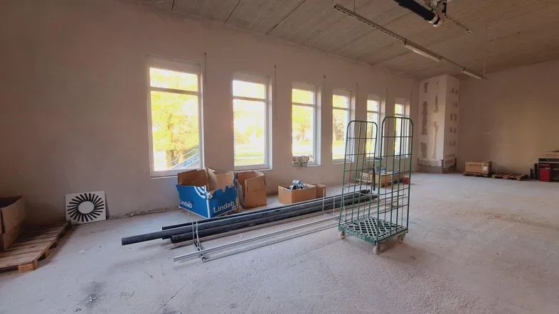 Gewerberaum im Rohbau mit mehreren Fenstern und Blick ins Grüne, bereit für den Ausbau.