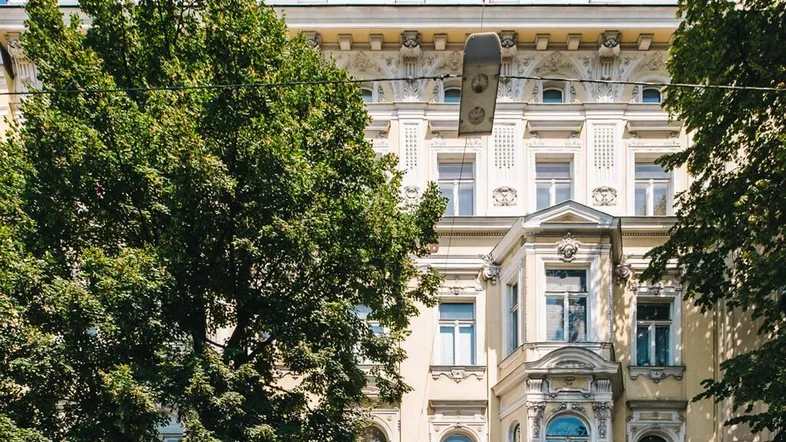 Elegante Fassade eines Altbaus mit reich verzierten Details und großen Fenstern.