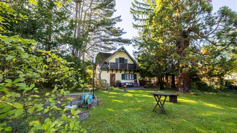 Charmantes Haus mit großem, gepflegtem Garten und altem Baumbestand, ideal für Entspannung im Freien.