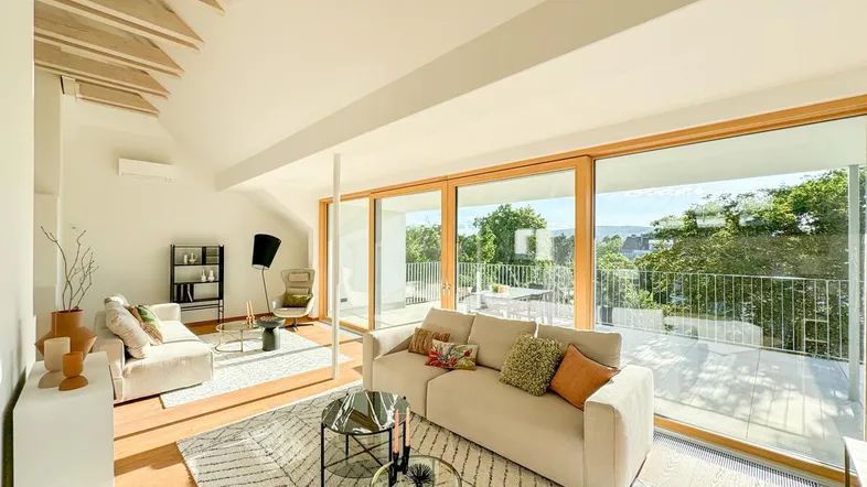 Helles, modernes Wohnzimmer mit Holzboden, großen Fenstern und Zugang zur Terrasse.