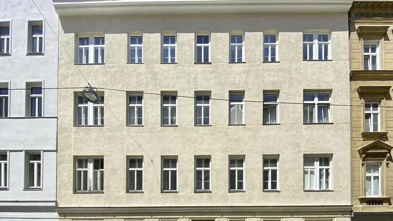 Klassische Fassade eines Mehrfamilienhauses mit mehreren Stockwerken und Dachausbauten.