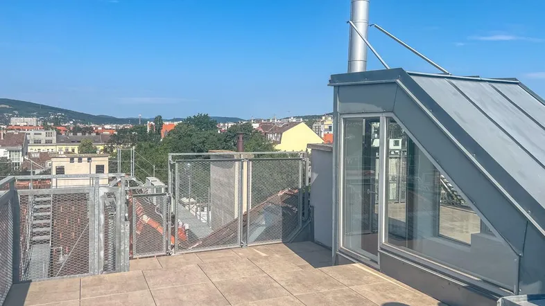 Dachterrasse mit Stadtblick und Zugang zum Gebäude, ideal für Entspannung im Freien.