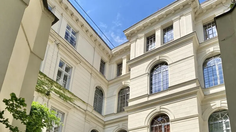 Klassische Fassade eines historischen Gebäudes mit vielen Fenstern und architektonischen Details unter blauem Himmel.