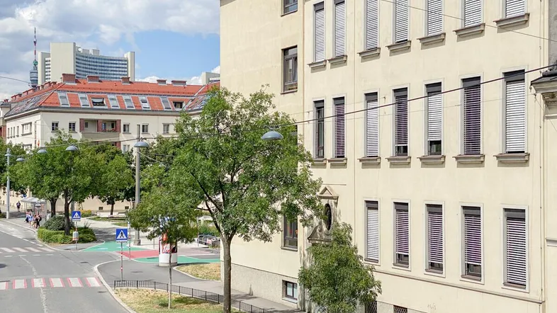 Ansicht eines Mehrfamilienhauses mit Jalousien und Blick auf die umliegende Stadtlandschaft.