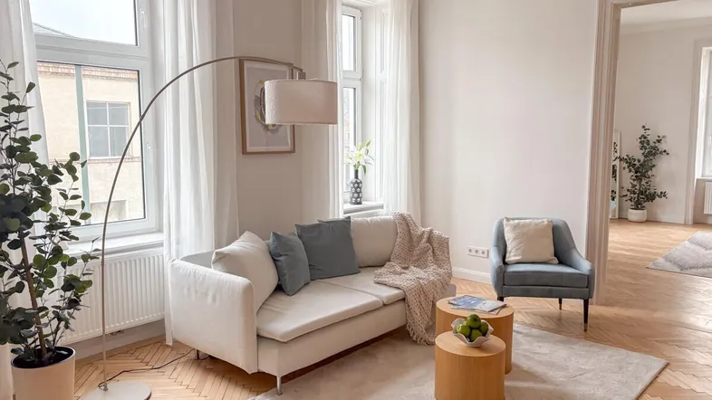 Helles Wohnzimmer mit Fischgrätparkett, beigem Sofa und modernen Möbeln, ideal zum Entspannen.