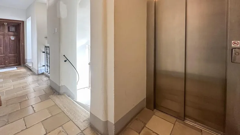 Gemeinschaftlicher Flur mit Fliesenboden, Treppenhaus und modernem Aufzug im Gebäude.