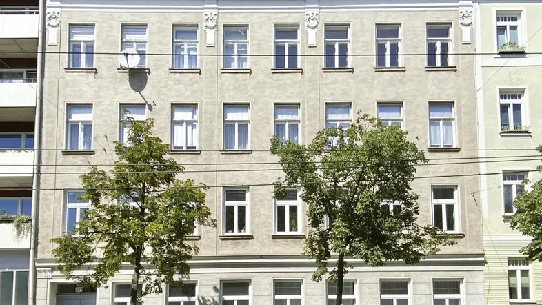 Fassade eines klassischen Mehrfamilienhauses mit vielen Fenstern und traditionellen Details.