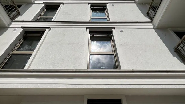 Ansicht der modernen Fassade eines Neubaus mit Balkonen und großen Fenstern von unten.