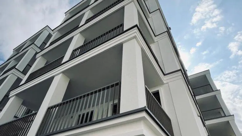 Dynamische Perspektive eines modernen Wohnkomplexes mit gestaffelten Balkonen und klarem Himmel.