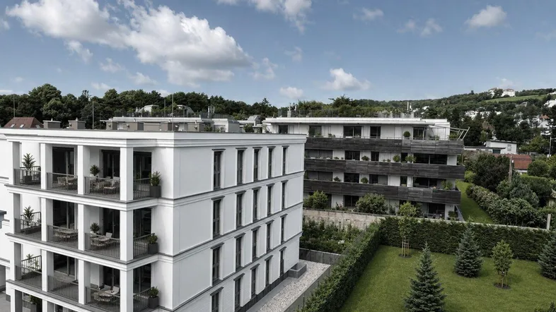 Moderne Wohngebäude mit eleganten Balkonen und gepflegter Gartenanlage in grüner Umgebung.