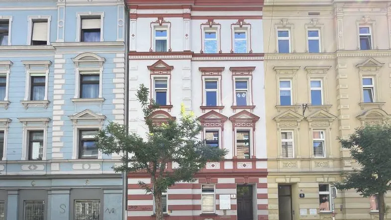 Historische Altbaufassade mit dekorativen Elementen in einer städtischen Umgebung.