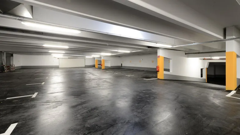 Geräumige Tiefgarage mit vielen leeren Stellplätzen, hellen Wänden und guter Beleuchtung.