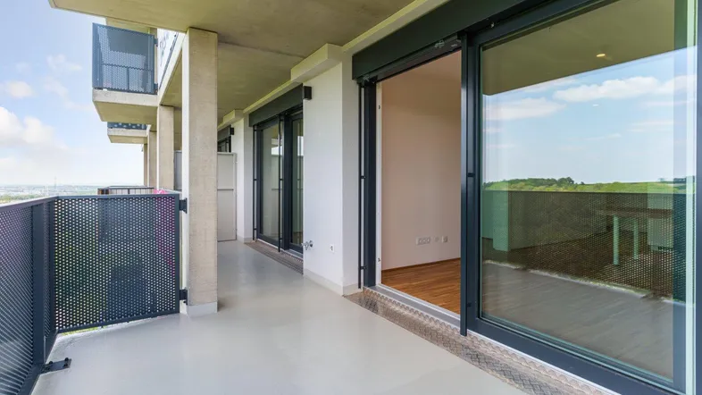 Geräumiger Balkon mit Blick ins Grüne und Schiebetüren zum hellen Innenbereich der Wohnung.