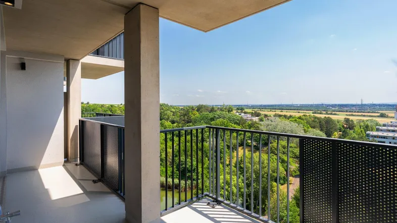 Geräumiger Balkon mit modernem Geländer und weitem Blick über grüne Landschaft und Wasser.