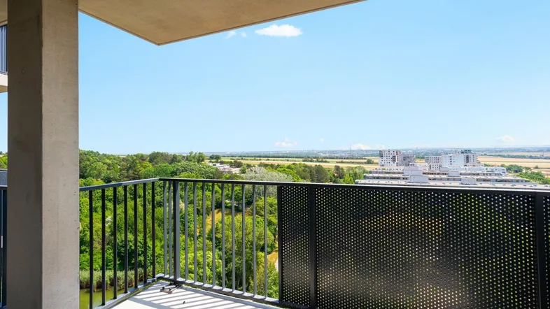 Geräumiger Balkon mit weitem Blick über grüne Landschaft, Wasser und die Stadt in der Ferne.