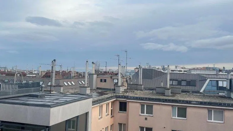 Blick über die Dächer der Stadt mit verschiedenen Gebäuden und einem bewölkten Himmel.