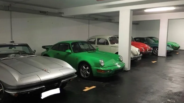 Geräumige Tiefgarage mit mehreren gepflegten Oldtimern, Betonboden und heller Beleuchtung.