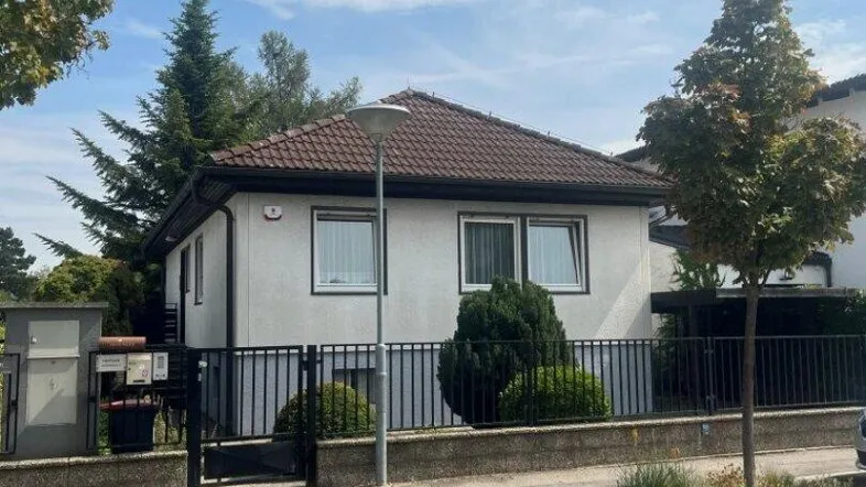 Vorderansicht des Einfamilienhauses mit gepflegtem Vorgarten und Zaun.