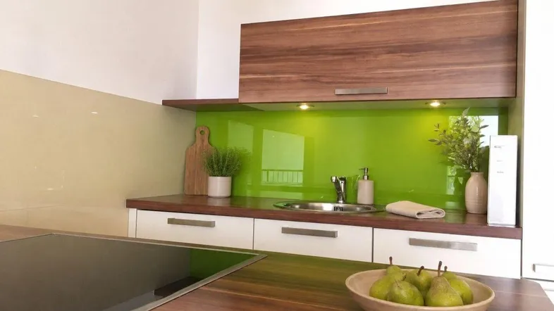 Moderne Küche mit Holzarbeitsplatte, grünem Spritzschutz und integriertem Induktionskochfeld.