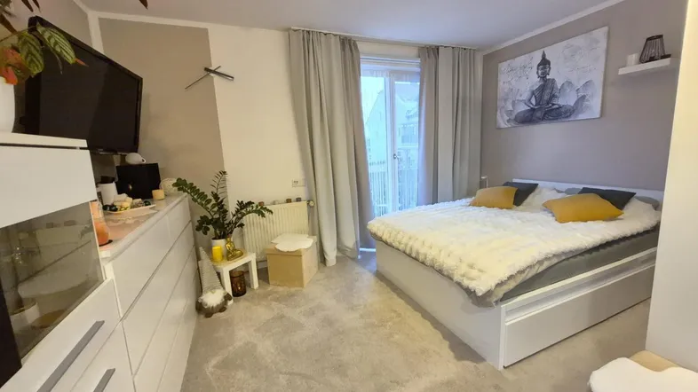 Helles Schlafzimmer mit gemütlichem Teppichboden, großem Bett und Zugang zum Balkon.