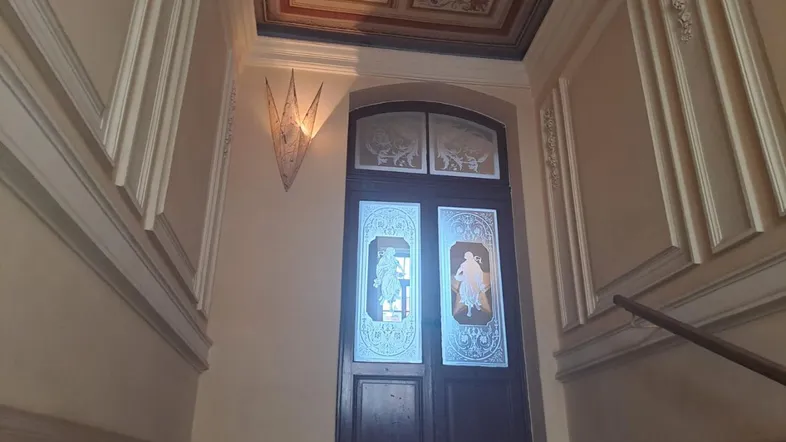 Repräsentativer Treppenabsatz mit kunstvoller Stuckdecke und verzierten Wänden in einem Altbau.