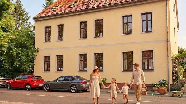 Historisches Gebäude mit gelber Fassade und roten Dachziegeln an einer ruhigen Straße.