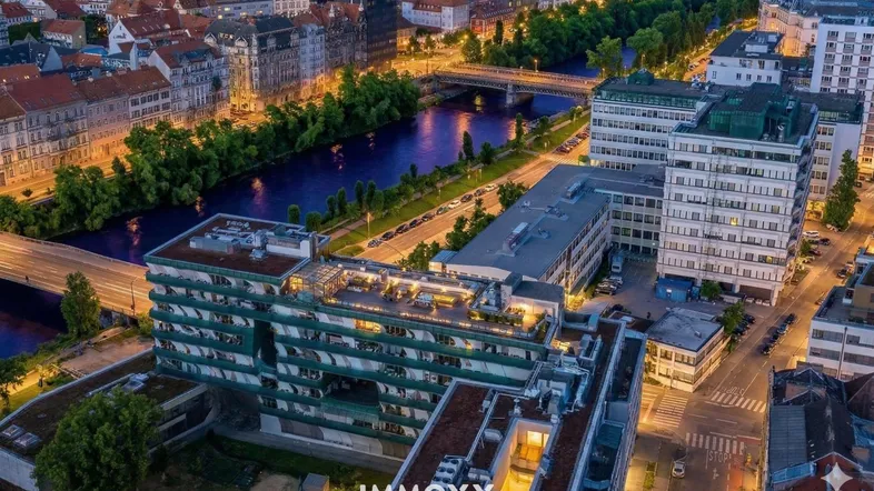 Luftaufnahme einer Stadt mit Fluss, Brücken und Gebäuden bei Abenddämmerung.
