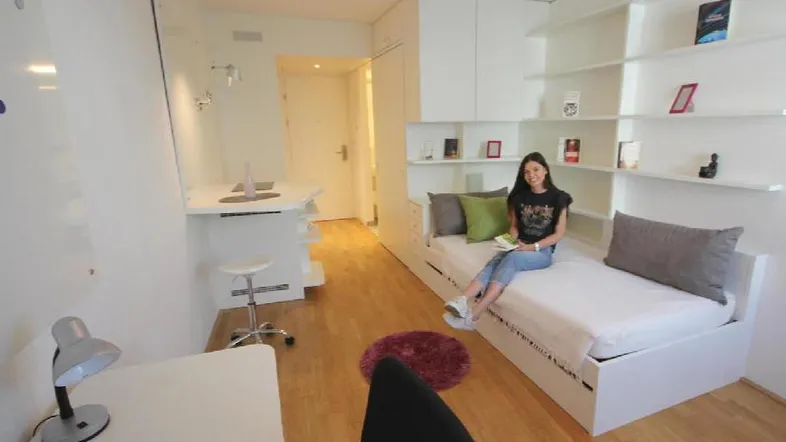 Helles Schlafzimmer mit Einzelbett, Schreibtisch und integrierten Regalen in modernem Stil.