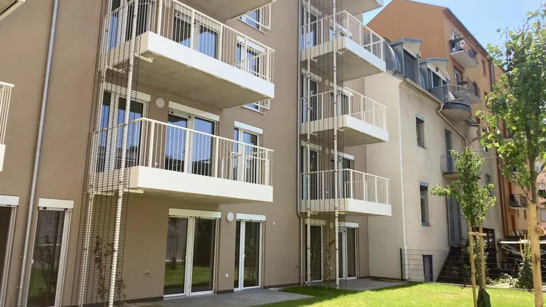 Moderne Wohnanlage mit Balkonen, Gartenflächen und Zugang zu den Erdgeschosswohnungen.