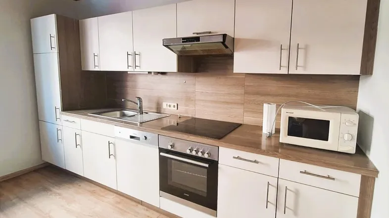 Moderne Einbauküche mit hellen Fronten, Holzdecke und integrierten Geräten, ideal für den täglichen Gebrauch.